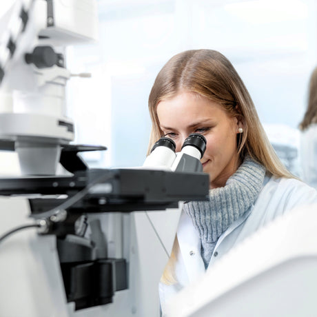 Wissenschaftlerin bei der Arbeit mit einem Askania Mikroskop in einem hellen Labor für präzise Mikroskopieanwendungen