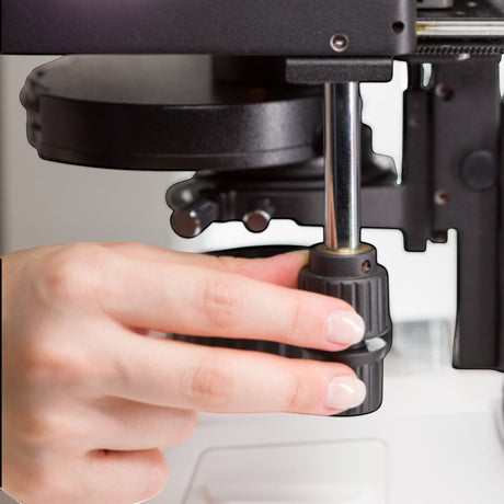 Hand bedient den Fokusknopf am ASKANIA Mikroskoptechnik ZEISS Primostar 3 Durchlichtmikroskop für präzise Schärfe