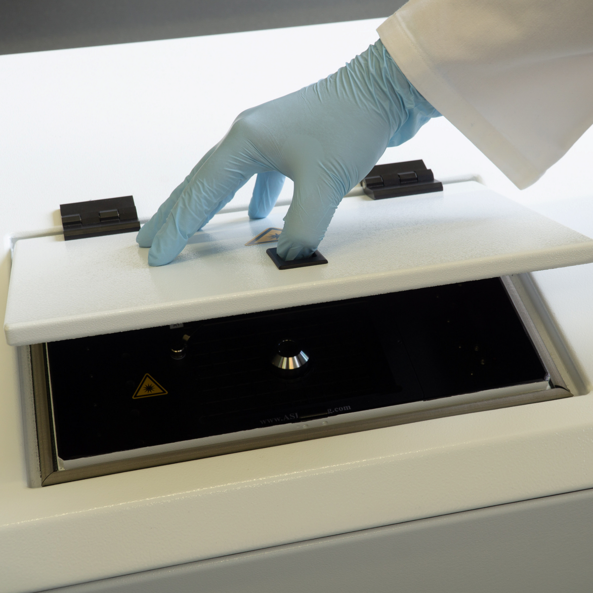 ASKANIA attomol Caleidoscan 100 Fluoreszenz-Imager mit geöffneter Abdeckung und Hand in blauem Einweghandschuh.
