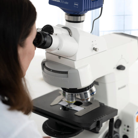 Wissenschaftlerin bei der Arbeit an einem modernen Zeiss Mikroskop mit Ölimmersionsobjektiv im Labor